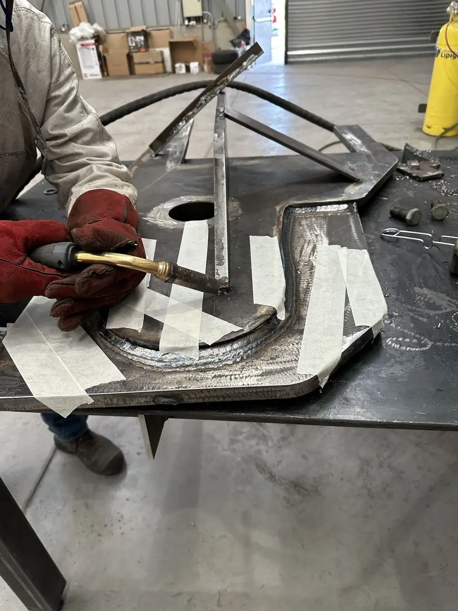 Soldador trabajando una pieza metálica en el taller